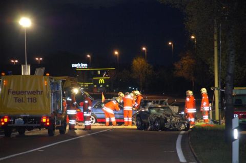 1976 Chevrolet Corvette - Emergency responders attend to a nighttime accident involving a severely damaged black sports car and a blue sedan.