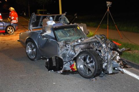 1976 Chevrolet Corvette - A severely damaged convertible sits on the roadside at night, with emergency personnel present.
