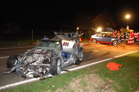 1976 Chevrolet Corvette - A severely damaged silver sports car sits on the side of the road at night, with emergency personnel and another vehicle in the background.