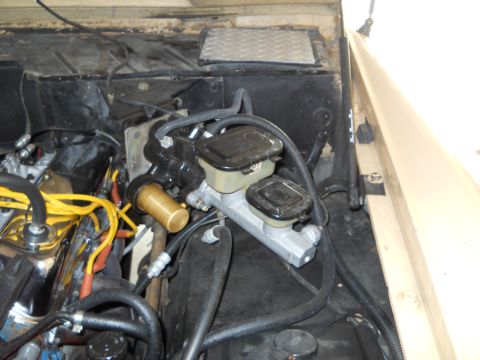 1976 Ford Bronco - Close-up of the brake master cylinder and fluid reservoirs in a vehicle's engine bay.