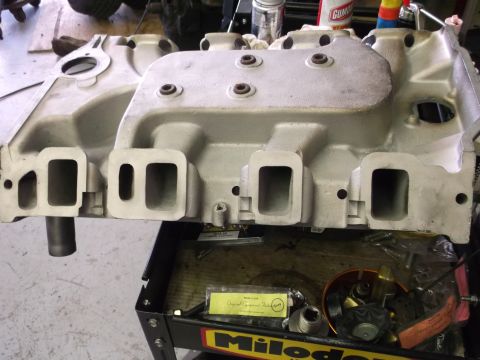 1967 Ford Mustang - Close-up of an engine intake manifold on a tool cart, with visible ports and mounting holes.
