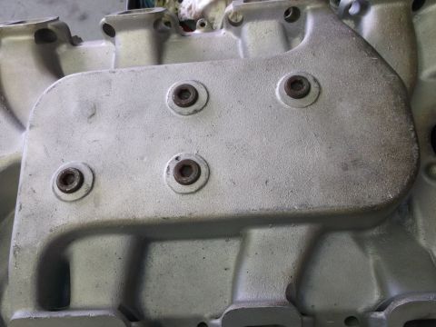 1967 Ford Mustang - A close-up view of a silver-colored engine intake manifold, showing its bolted surface and intake ports.
