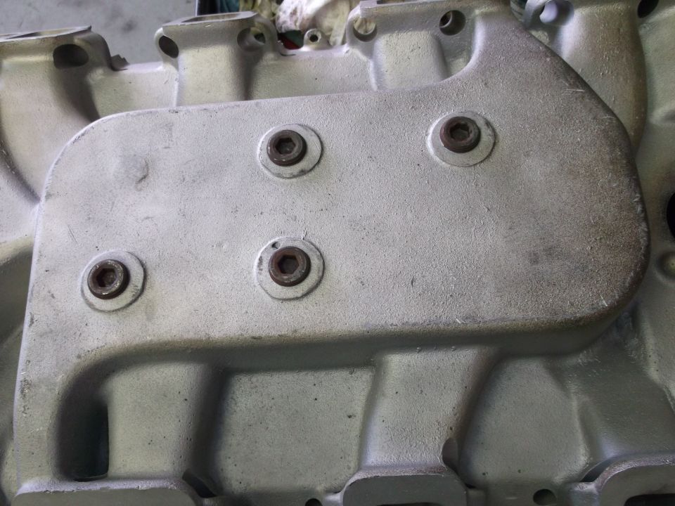 Close-up of a silver engine intake manifold with hex bolts