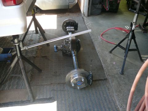1988 Ford Bronco - A rear axle assembly, likely for a vehicle, is shown disassembled and supported by jack stands.