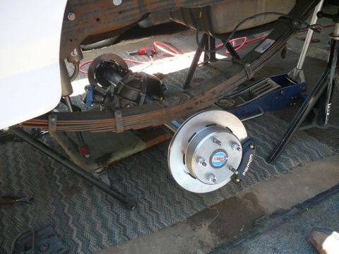 1988 Ford Bronco - Close-up of a rear axle and brake assembly, a Wilwood caliper and a slotted rotor, likely undergoing maintenance or upgrade.