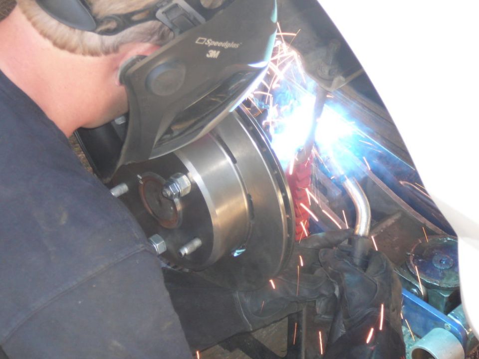 Welder in mask works on brake rotor and hub assembly of a vehicle
