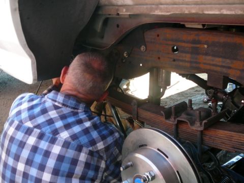 1988 Ford Bronco - Mechanic performs maintenance on vehicle suspension system, focusing on brake components.