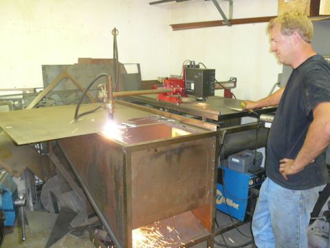 1988 Ford Bronco - A man is using a plasma cutter to cut a piece of metal in a workshop setting.