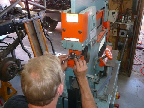 1988 Ford Bronco - Man operates a metal press, with vehicle parts in the background.