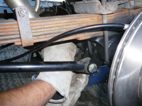 1988 Ford Bronco - A mechanic works on the suspension system, showing leaf springs and brake components.