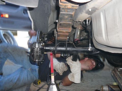 1988 Ford Bronco - A mechanic performs work on the rear axle and disc brakes of a 1988 Ford Bronco.