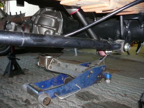 1988 Ford Bronco - The rear axle and suspension components of a vehicle are visible, supported by jack stands and a floor jack.