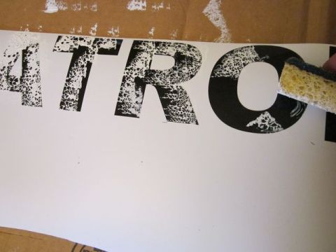 1991 Ford LTD Crown Victoria - A sponge is used to clean black textured letters on a white surface, revealing the word "ATRO".