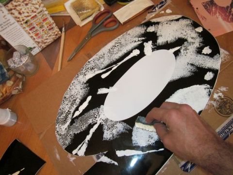 1991 Ford LTD Crown Victoria - A person is painting a car emblem with white paint and a sponge. Supplies are on the table.