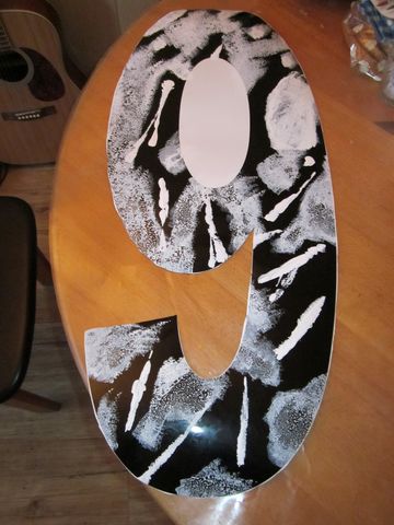 1991 Ford LTD Crown Victoria - A decorative number 9 with a black and white abstract design sits on a wooden surface next to a guitar.