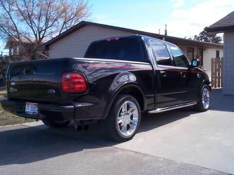 1977 Ford Bronco - Driver-side rear three-quarter view of a lowered black Ford F-150 SuperCrew Harley-Davidson edition parked on a residential concrete drivew…