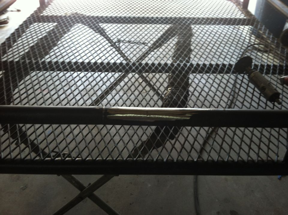Roof rack with diamond-shaped metal mesh and a damaged horizontal bar