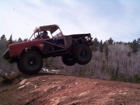 1977 Ford Bronco - This heavily modified off-road vehicle is captured mid-jump over a dirt hill.