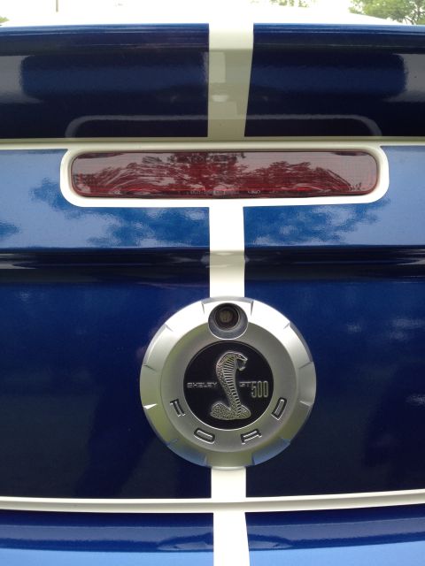 2007 Ford Mustang - Rear view of a blue 2007 Ford Mustang Shelby GT500, white racing stripes and the iconic Cobra emblem.