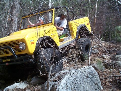 1977 Ford Bronco - A yellow topless early Ford Bronco with a black exterior roll cage, black tube front bumper with Warn winch, cut fenders and diamond-plate…