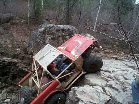 1977 Ford Bronco - Overhead view of a red topless early Ford Bronco with a white full exterior roll cage and white striped graphics climbing steeply nose-up o…