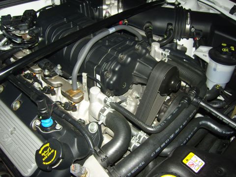 2007 Ford Mustang - Close-up of a supercharged engine bay, likely from a 2007 Ford Mustang, showing the supercharger and associated components.