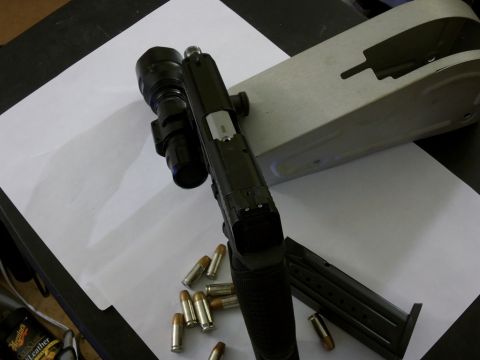 2000 Mercury Grand Marquis - A pistol with a tactical flashlight and ammunition is displayed on a table.