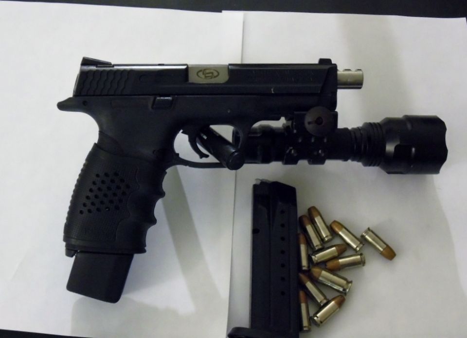 Black pistol with mounted flashlight and magazine with bullets