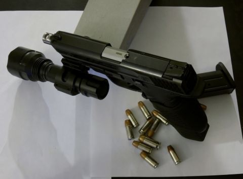 2000 Mercury Grand Marquis - A handgun with a tactical flashlight attached and several rounds of ammunition are laid out on a white surface.
