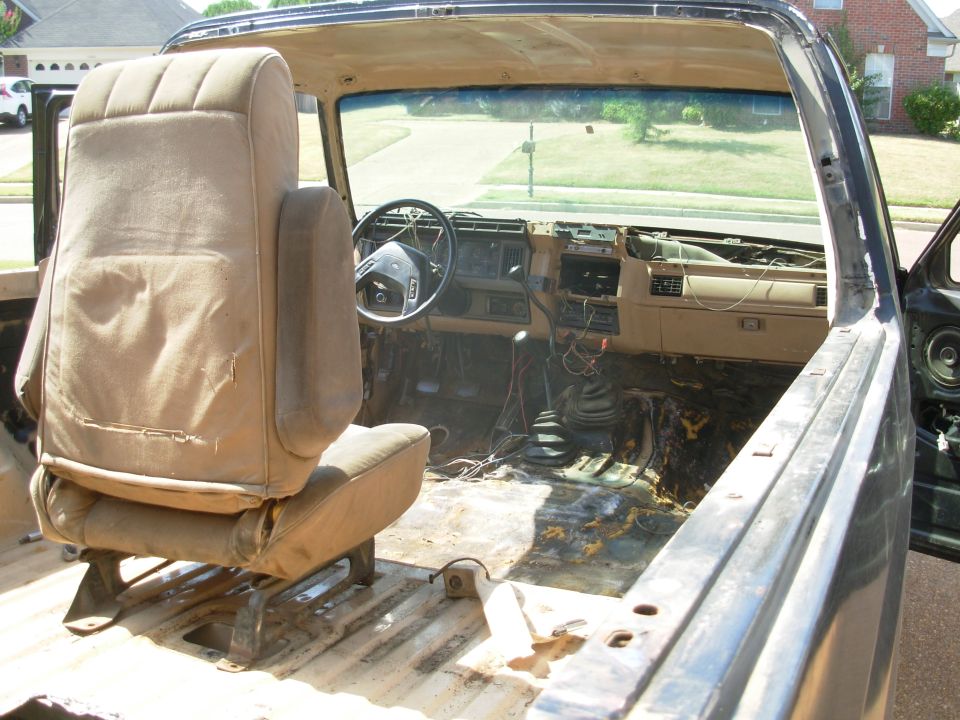 Stripped Ford Bronco interior with tan seat, dash and bare metal floor