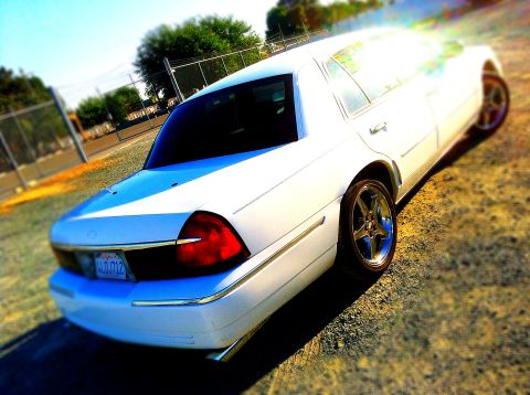 1999 Mercury Grand Marquis - A white sedan is parked outdoors on a sunny day, showing its rear end and side profile.