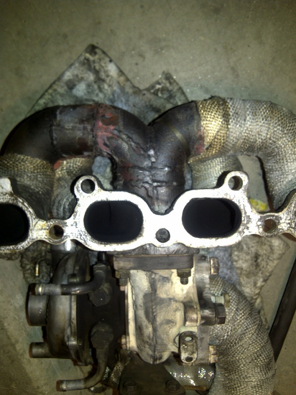 Turbocharger and exhaust manifold with heat wrap, showing soot and wear