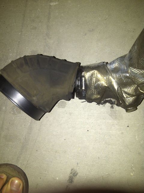 1995 Ford Probe - This exhaust pipe shows significant damage to its heat shielding and a torn rubber connection.