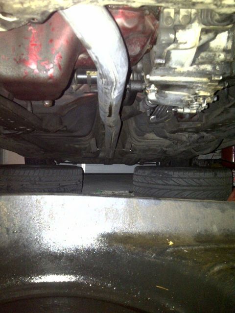 1995 Ford Probe - Underside view of a vehicle's exhaust and transmission, with tires resting on blocks.