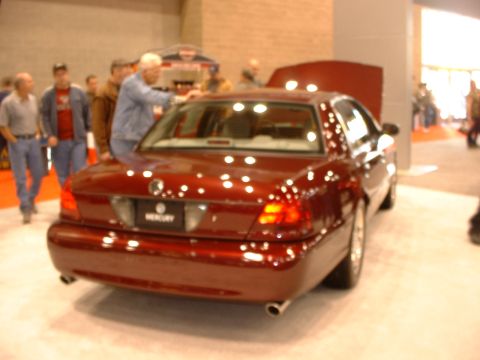 1999 Ford Crown Victoria - A red Mercury Grand Marquis is displayed with its hood open at an auto show.