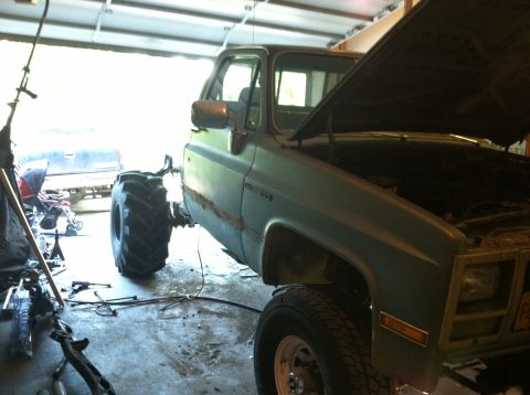 1983 Chevrolet C/K Pickup - This 1983 Chevrolet C/K Pickup truck is undergoing modifications in a garage, oversized tires and an open hood.