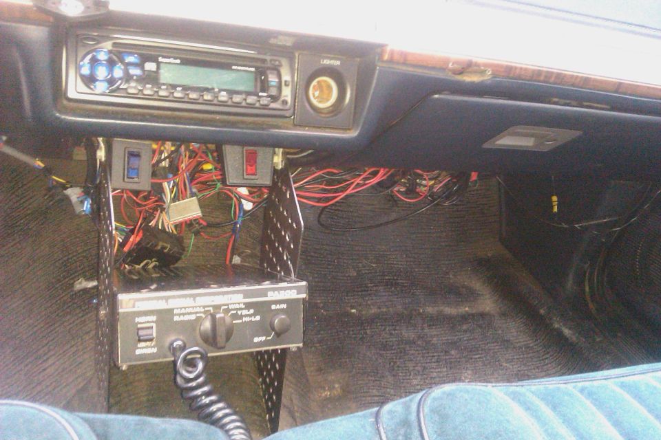 Car interior showing aftermarket stereo, CB radio, and wiring under the dash