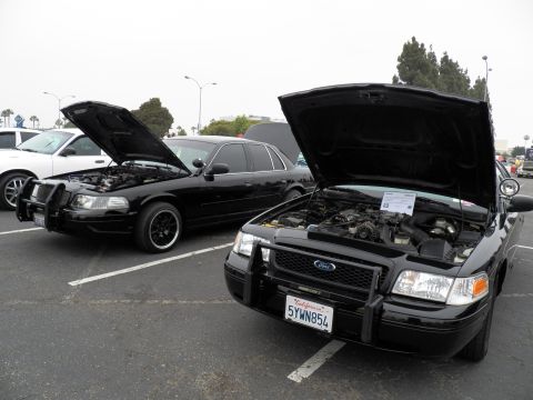 2003 Ford Crown Victoria - Pair of black Crown Victorias with raised hoods, the nearer wearing California plate 5YWN854.