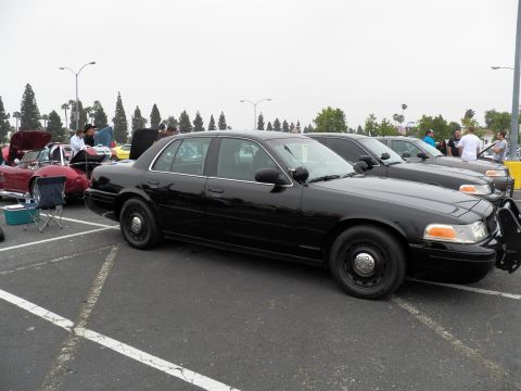 2003 Ford Crown Victoria - Black Crown Victoria on plain steel wheels parked beside a red coupe at a parking lot meet.