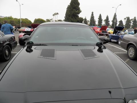 2003 Ford Crown Victoria - Close view of a black vented hood and windshield with a row of show cars in the background.