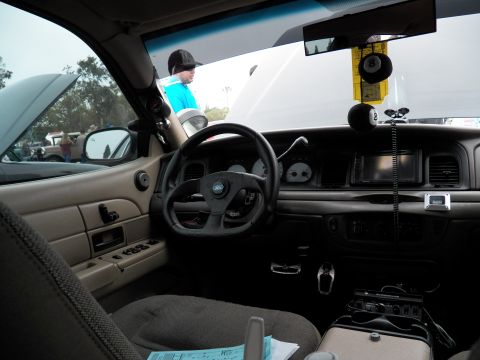 2003 Ford Crown Victoria - Tan-and-black sedan interior showing custom wheel, dash, CB radio and hanging 8-ball.