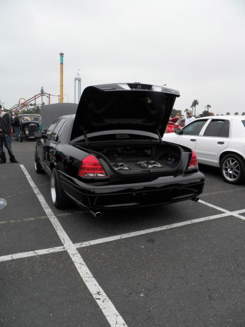 2003 Ford Crown Victoria - Rear three-quarter of a lowered black Crown Victoria, trunk open over an audio setup.