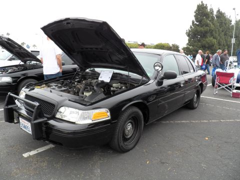 2003 Ford Crown Victoria - Black Crown Victoria interceptor with brush guard and spotlight, hood up, California plate.