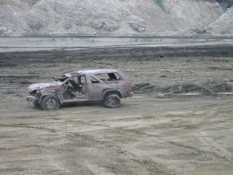 1985 Ford Bronco - This heavily damaged SUV is abandoned in a desolate, muddy landscape.