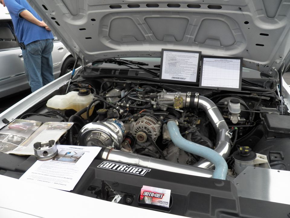 Engine bay of white car with Vortech supercharger and AutoRnet polished intake piping