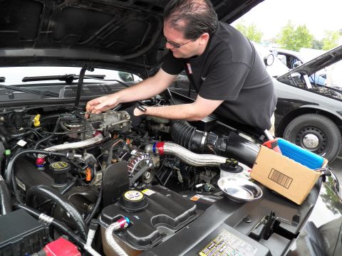 2003 Ford Crown Victoria - Man in glasses works inside an engine compartment featuring a polished intake pipe and exposed alternator.