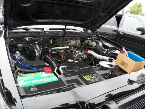 2003 Ford Crown Victoria - Detailed engine compartment showing a green Interstate battery, polished intake tube and parts box.