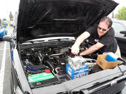 2003 Ford Crown Victoria - man reaches into the engine bay of a black sedan fitted with an Interstate battery and aftermarket parts.