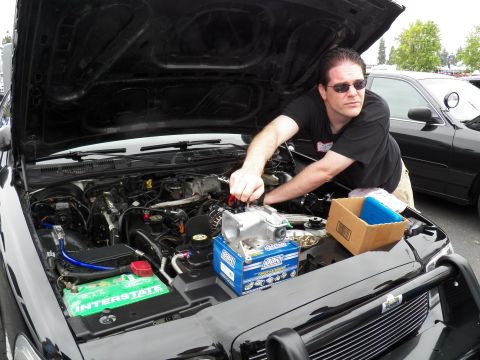 2003 Ford Crown Victoria - Close engine-bay view of a black sedan with green Interstate battery as a man in sunglasses installs parts.