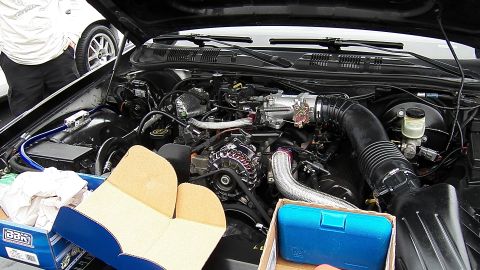 2003 Ford Crown Victoria - Close engine-bay shot of a black sedan showing chrome intake piping and aftermarket components.